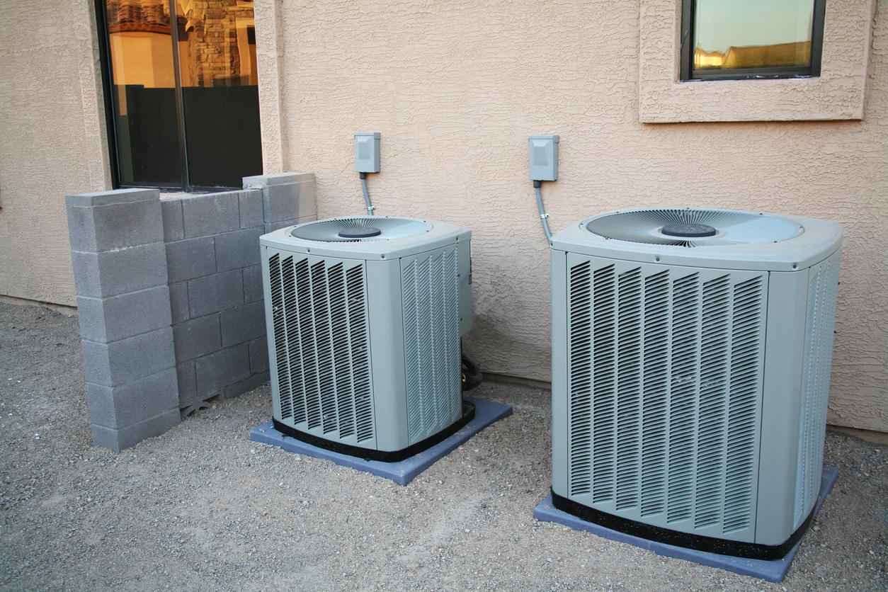 A couple of brand new air conditioners sitting next to a new home.
