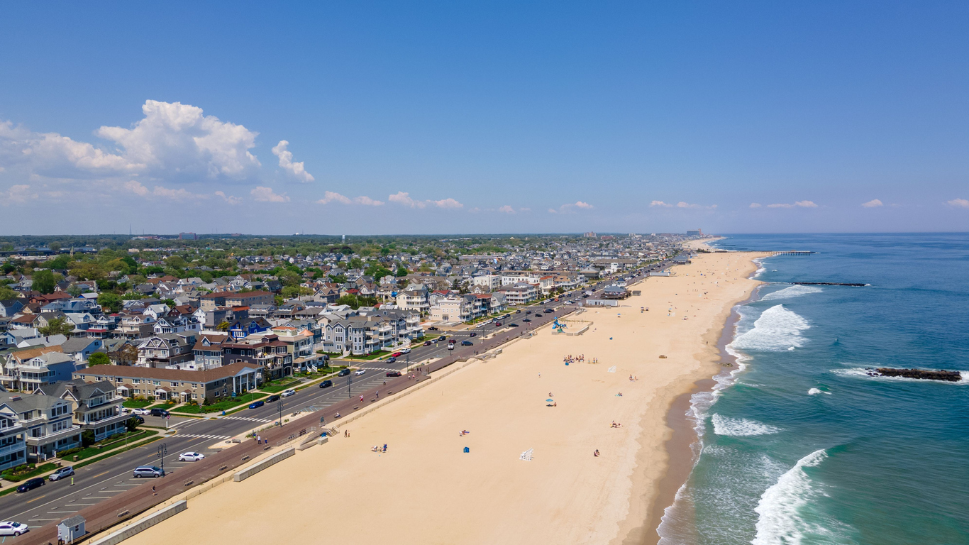 A drone shot of the Belmar Beach and coastal road and buildings on a sunny day in Belmar, New Jersey, USA.