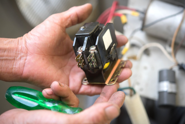 Man holding an HVAC contactor part, showing how it works. 